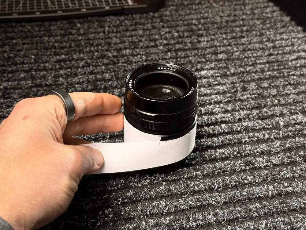 Voigtlaender Linse wird mit einem Papierstreifen vermessen